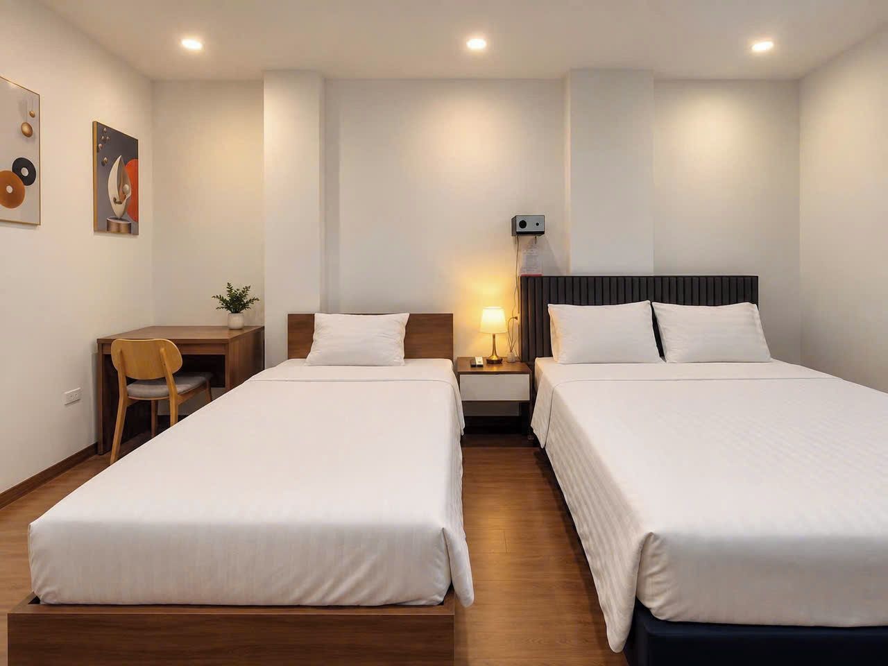 A hotel room with two beds, a desk, and a chair.