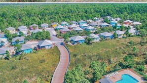 An aerial view of a residential area with houses, a winding road, and a swimming pool. - Spacious Gulf Shores Beach House with Pool Access and Ocean Views (Gulf Shores)