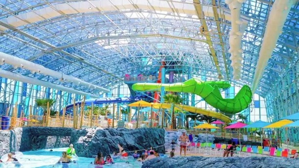 An indoor water park with a large glass ceiling, multiple water slides, and a pool area. - Spacious Gulf Shores Beach House with Pool Access and Ocean Views (Gulf Shores)