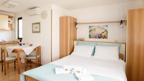 A bedroom with a bed, bedside table, and a desk with chairs. - Apartments Alba - 1 Bedroom Apartment (Rovinj)