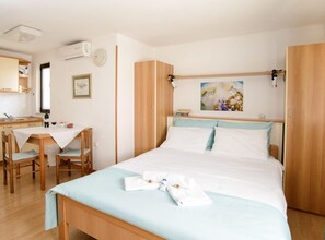 A bedroom with a bed, bedside table, and a desk with chairs. - Apartments Alba - 1 Bedroom Apartment (Rovinj)