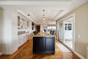 A spacious kitchen with a central island, white cabinetry, and a large window.