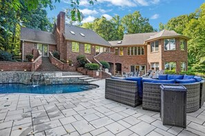 A brick house with a swimming pool, outdoor seating, and a stone staircase.