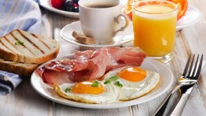 En frukosttallrik med ägg, prosciutto, rostat bröd och ett glas apelsinjuice.
