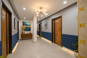 Un pasillo de hotel con paredes azules y blancas, puertas de madera y una columna central.
