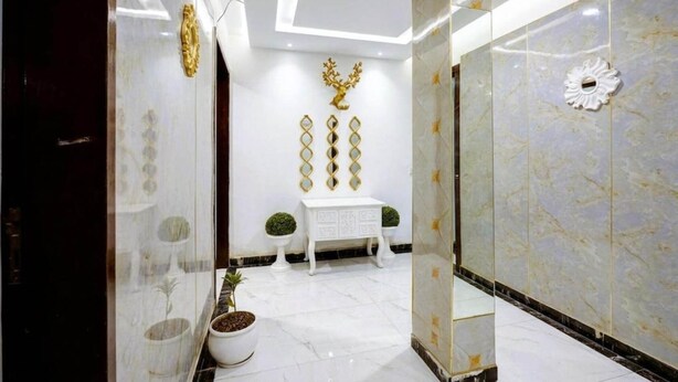A modern interior with a marble wall, a white console table, and decorative gold elements. - Hotel The Dreams Inn & Banque (Kharar)