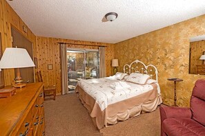 Une chambre à coucher avec un lit, une commode, une chaise et une lampe.