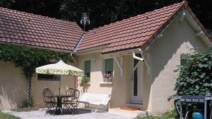 A small house with a tiled roof, a patio with a table and chairs, and a garden. - Gîte des Chênes, located in the heart of Béarn. (Arthez-de-Béarn)
