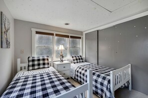 Ein Schlafzimmer mit zwei Betten, einem Nachttisch, einer Lampe und einem Fenster.