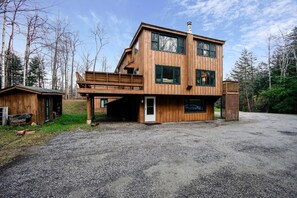 Eine mehrstöckige Holzhütte mit überdachter Veranda, Garage und einem Schotterweg.