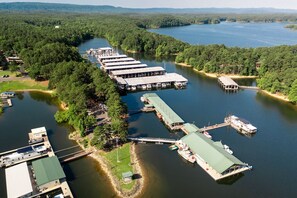 An aerial view of a lakeside property with multiple docked boats, a marina, and a large building with a green roof. - Arkansas Rest and Relaxation In Nature in this Lake Ouachita Rental (Mount Ida)