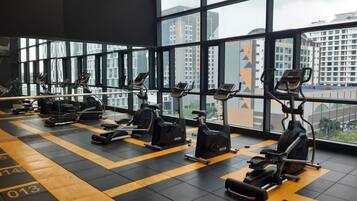 A gym with exercise equipment and large windows offering a city view.