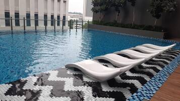 A swimming pool with a tiled edge and a white lounge chair.
