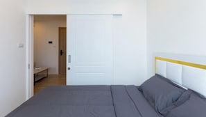 A bedroom with a bed, a door, and a bench in the adjacent room.