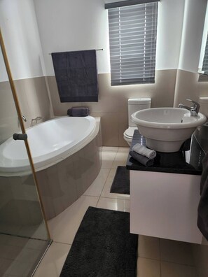 Ein modernes Badezimmer mit einer freistehenden Badewanne, einem großen Waschbecken und einer Toilette.