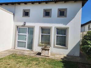 Ein zweigeschossiges Gebäude mit weißer Fassade, einer Haustür und drei Fenstern im zweiten Stock.
