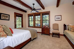Un dormitorio con cama, escritorio, silla y ventanas amplias.