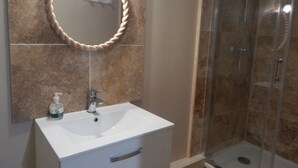 A bathroom with a white sink, a mirror with a rope frame, and a glass shower enclosure. - Beautiful 300 m apartment near the train station and Sillon Beach, within the city walls (Saint-Malo)