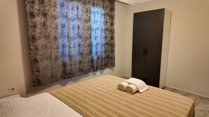 Een hotelkamer met een bed, een groot abstract schilderij, een donkere kast en een handdoek op het bed.
