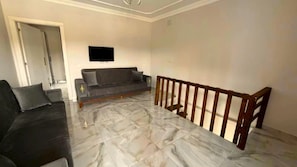 A living room with a sofa, a coffee table, and a wooden railing.