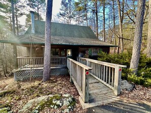 A cabin with a wooden deck, a covered porch, and a chimney.