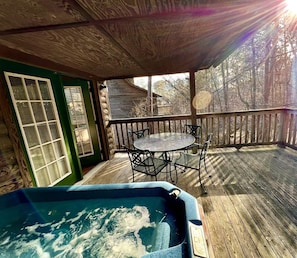 Una terraza de madera con un jacuzzi, una mesa y sillas, y una puerta verde.