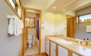 A bathroom with a toilet, sink, and mirror.