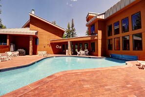 A modern house with a swimming pool, outdoor seating, and large windows.