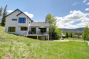 A two-story house with a balcony, a covered patio, and a view of mountains.