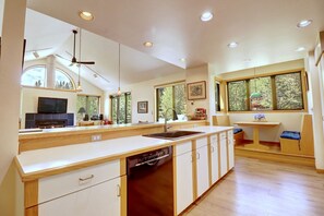 A modern kitchen with a dishwasher, a large island, and a dining area with a bench.