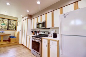 A modern kitchen with white cabinets, a stainless steel stove, a microwave, and a refrigerator.