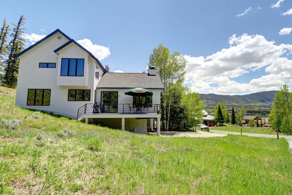 A two-story house with a balcony, a covered patio, and a view of mountains.