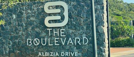 A stone wall with a sign for 'The Boulevard' on Albizia Drive.
