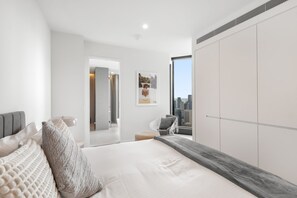 A modern bedroom with a large bed, a city view, and a walk-in closet. - Live in the clouds! 3BD luxury apt. in Southbank (Southbank)