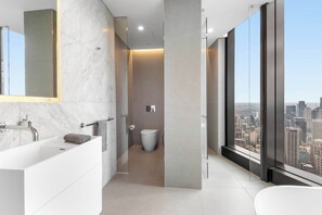 Ein modernes Badezimmer mit großem Spiegel, einer Badewanne und einer Toilette.