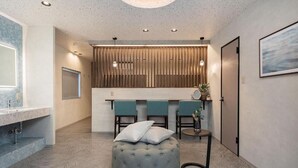 Een moderne badkamer met een marmeren aanrecht, een ronde poef en een wand van houten panelen.