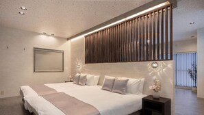 Een moderne hotelkamer met een groot bed, een wand van houtpanelen, een nachtkastje met een vaas en een raam met zonwering.