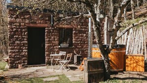 Un edificio rústico de piedra con una puerta, una ventana pequeña y un banco de madera afuera.