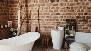 Un baño con una bañera grande, un lavabo y un espejo.