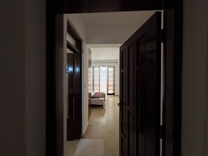 A hallway leading to a bedroom with a bed, a window with curtains, and a door. - NEW, ”villa” with a view, new design- pics in a few days (Mombasa)