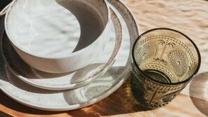 Ein Stapel weißer Keramikteller und ein dekoratives Glas mit aufwendigen Mustern.