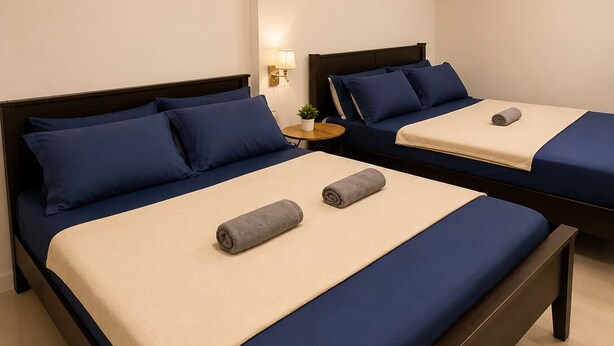 A hotel room with two beds, each with blue bedding and a beige accent. There are decorative hanging lights above the beds. - Tsinoy Villa (Pandi)