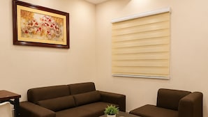 A modern living room with a sectional sofa, a small table with a plant, and a window with blinds. - Tsinoy Villa (Pandi)