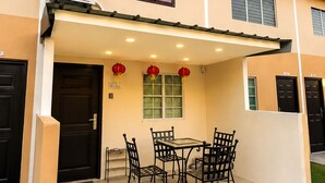 A two-story building with a covered patio area featuring a table and chairs, a window with a view, and an air conditioning unit. - Tsinoy Villa (Pandi)