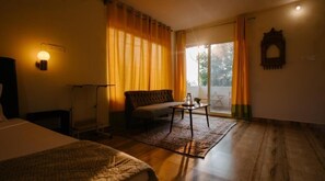 Una habitación con cama, sofá, una mesita y ventana con cortinas.