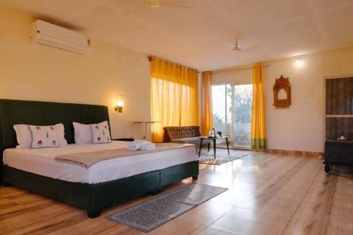 A bedroom with a large bed, a desk, a chair, and a lamp.