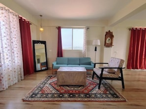 A living room with a sofa, ottoman, chair, and a patterned rug. - 360 Agonda (Canacona)