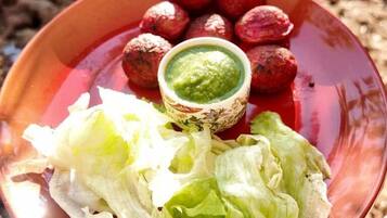 Un plato con alimentos y un bol de salsa verde.