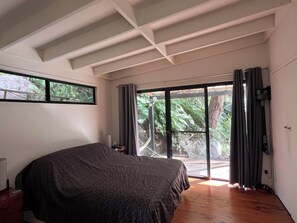 Ein Schlafzimmer mit einem Bett, einem Fenster und einer Glastür, die auf einen Balkon führt.