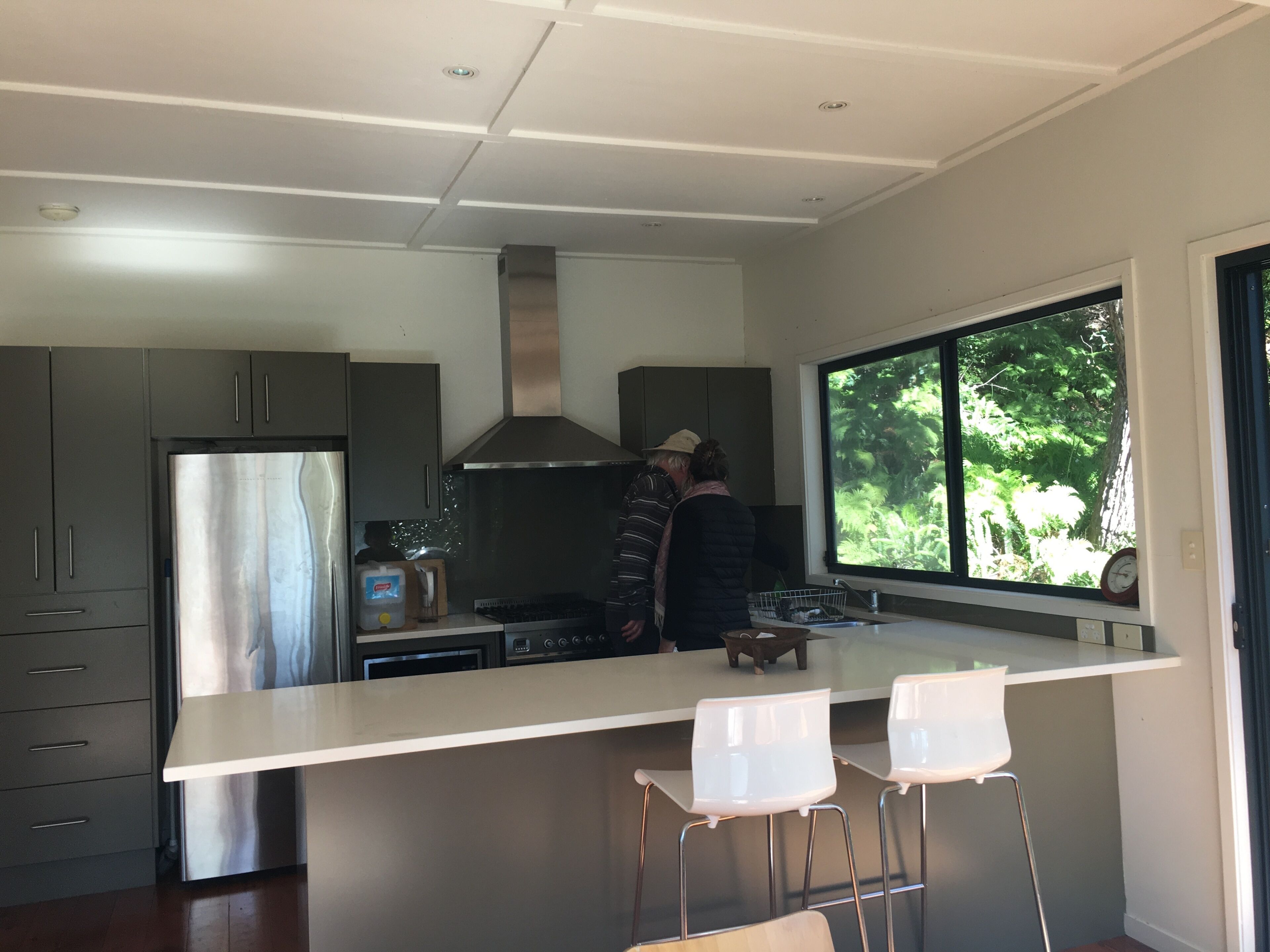 Uma cozinha moderna com uma ilha grande, eletrodomésticos de aço inoxidável e vista para o verde lá fora.